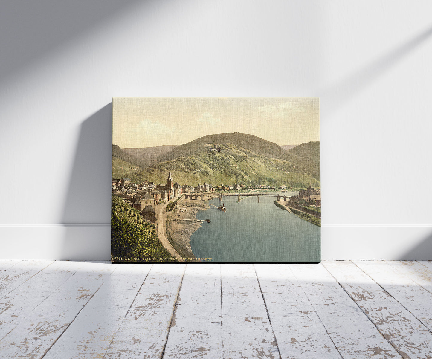 A picture of Bernkastel (i.e., Bernkastel-Kues) and Burg Landshut, Moselle, valley of, Germany, a mockup of the print leaning against a wall