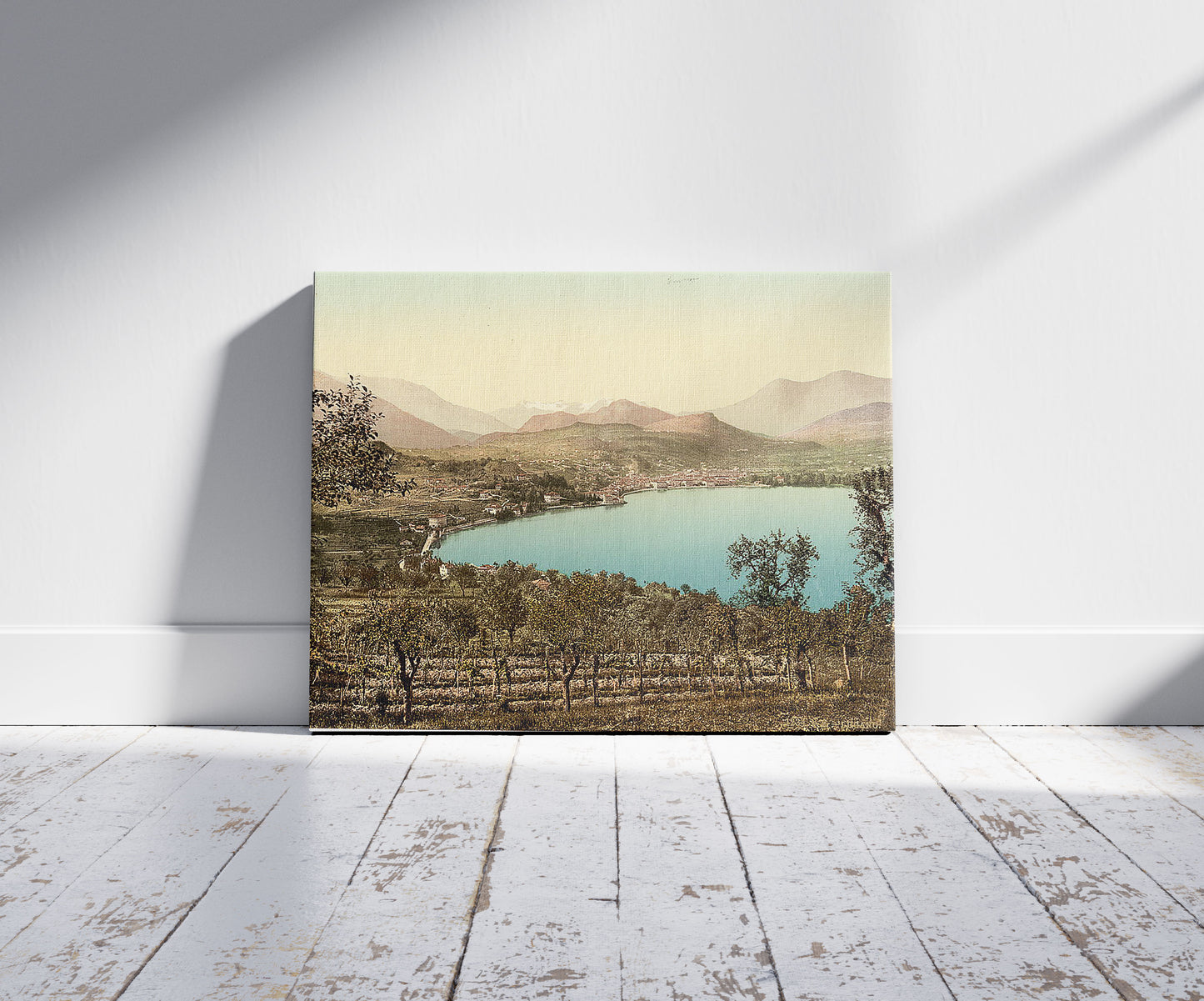 A picture of Lake of Lugano, view of the lake, the town, and the Alps, taken from Paradiso, Tessin, Switzerland, a mockup of the print leaning against a wall