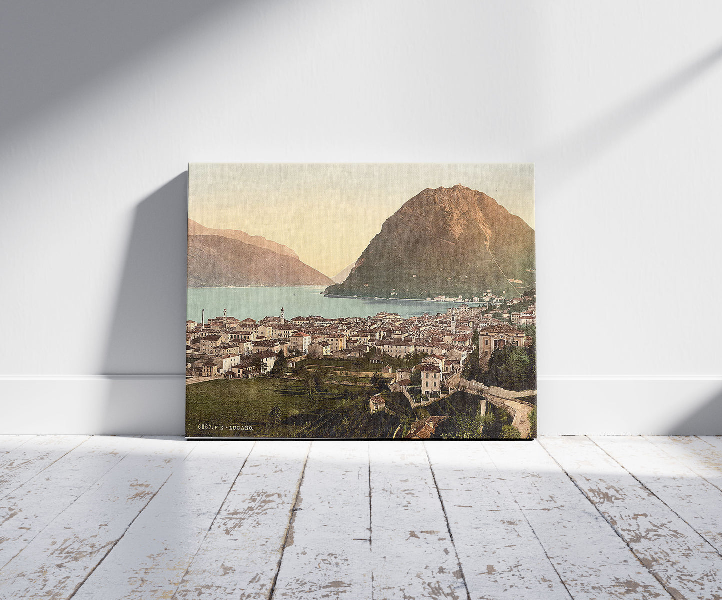 A picture of Lugano, general view, Tessin, Switzerland , a mockup of the print leaning against a wall