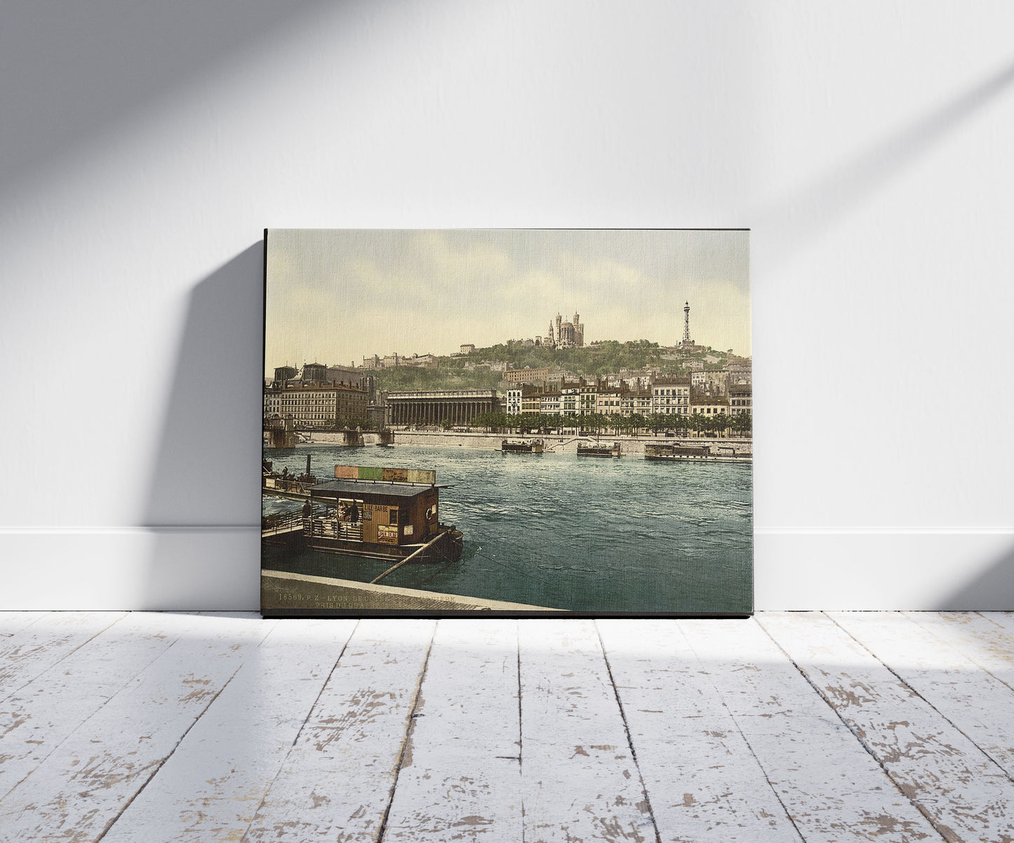 A picture of The Hill of Fourvière from St. Antoine Quay, Lyons, France, a mockup of the print leaning against a wall