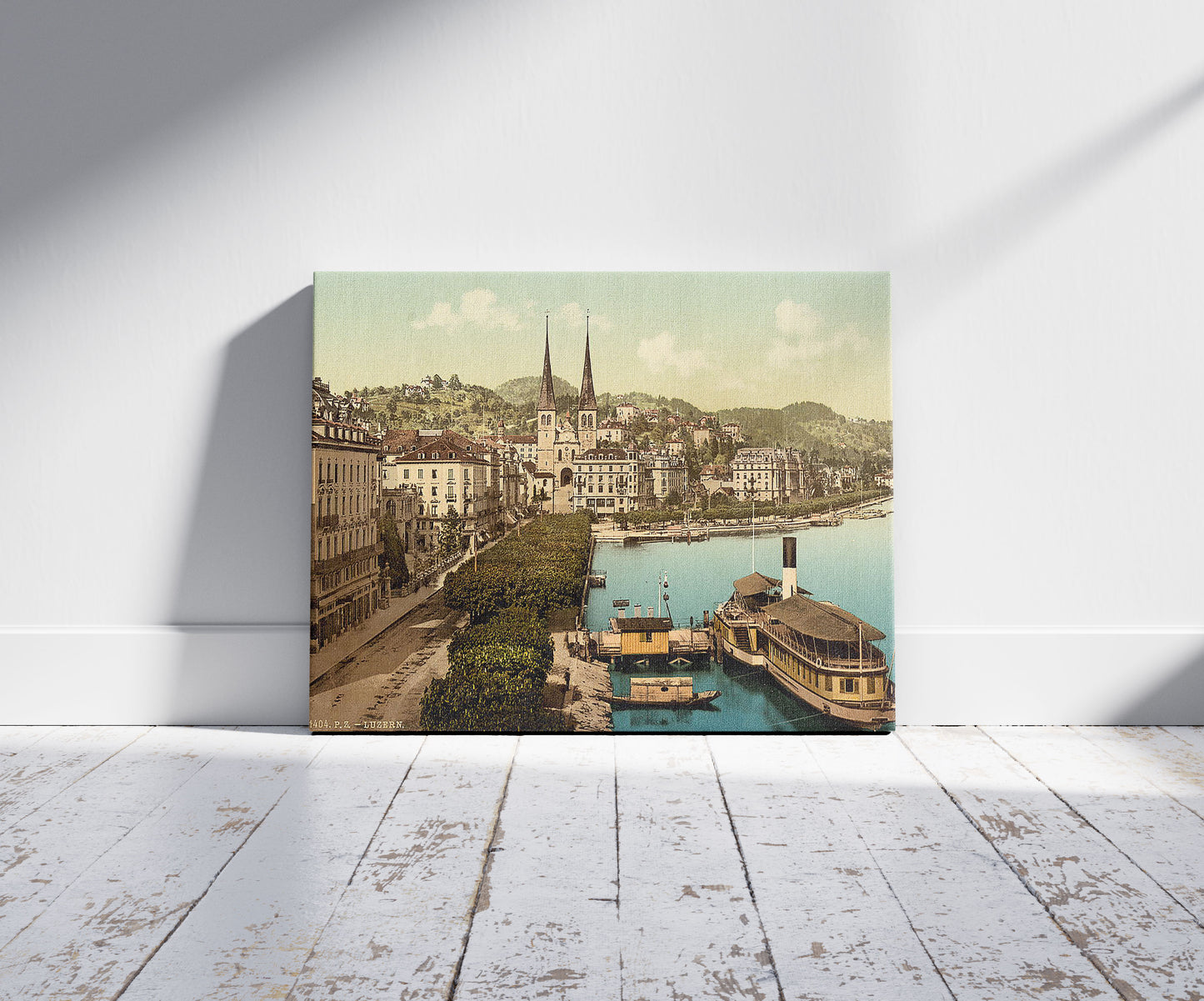 A picture of The quay, Hotels Schweizerhof and National and Cathedral from the Swan Hotel, Lucerne, Switzerland, a mockup of the print leaning against a wall