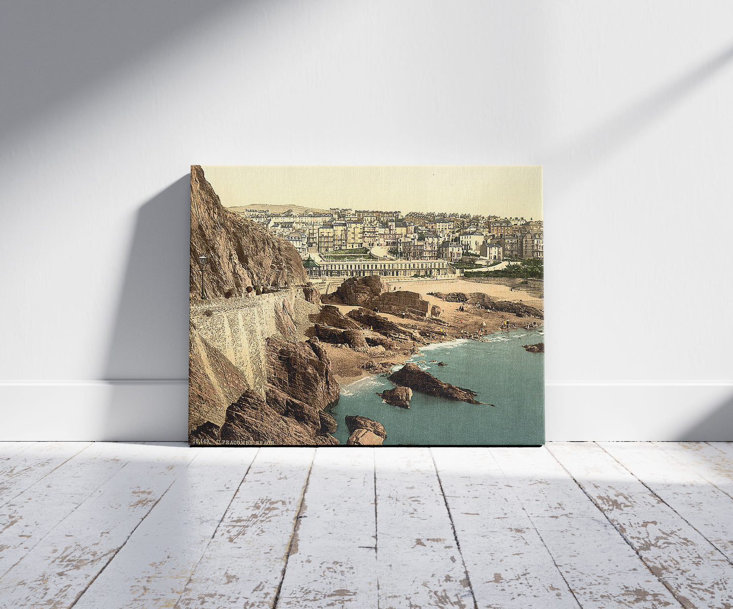 A picture of Town and beach from Capstone, Ilfracombe, England, a mockup of the print leaning against a wall