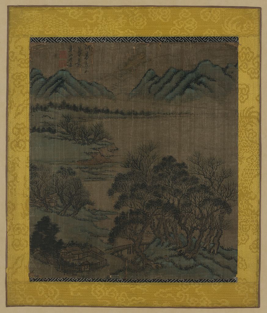 A picture of A residential compound with fence and outbuildings near grove of trees and small bridge, with bay and mountains in the background