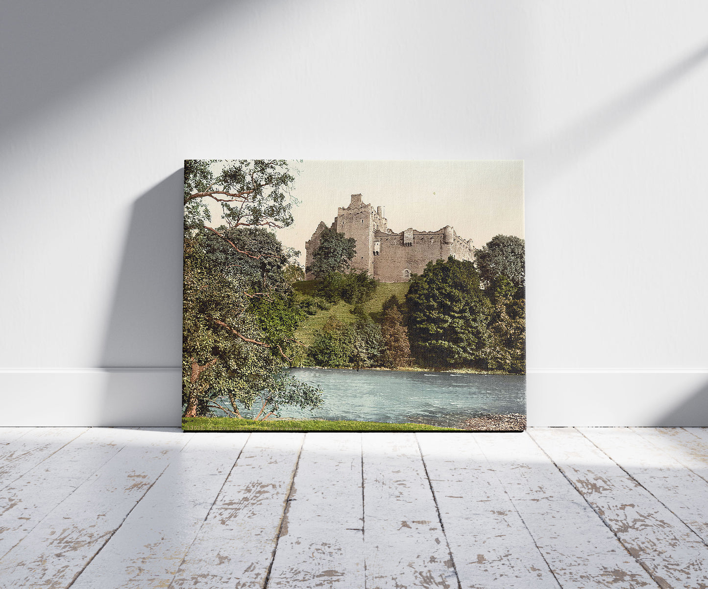 A picture of Doune Castle from the Teith, Scotland, a mockup of the print leaning against a wall