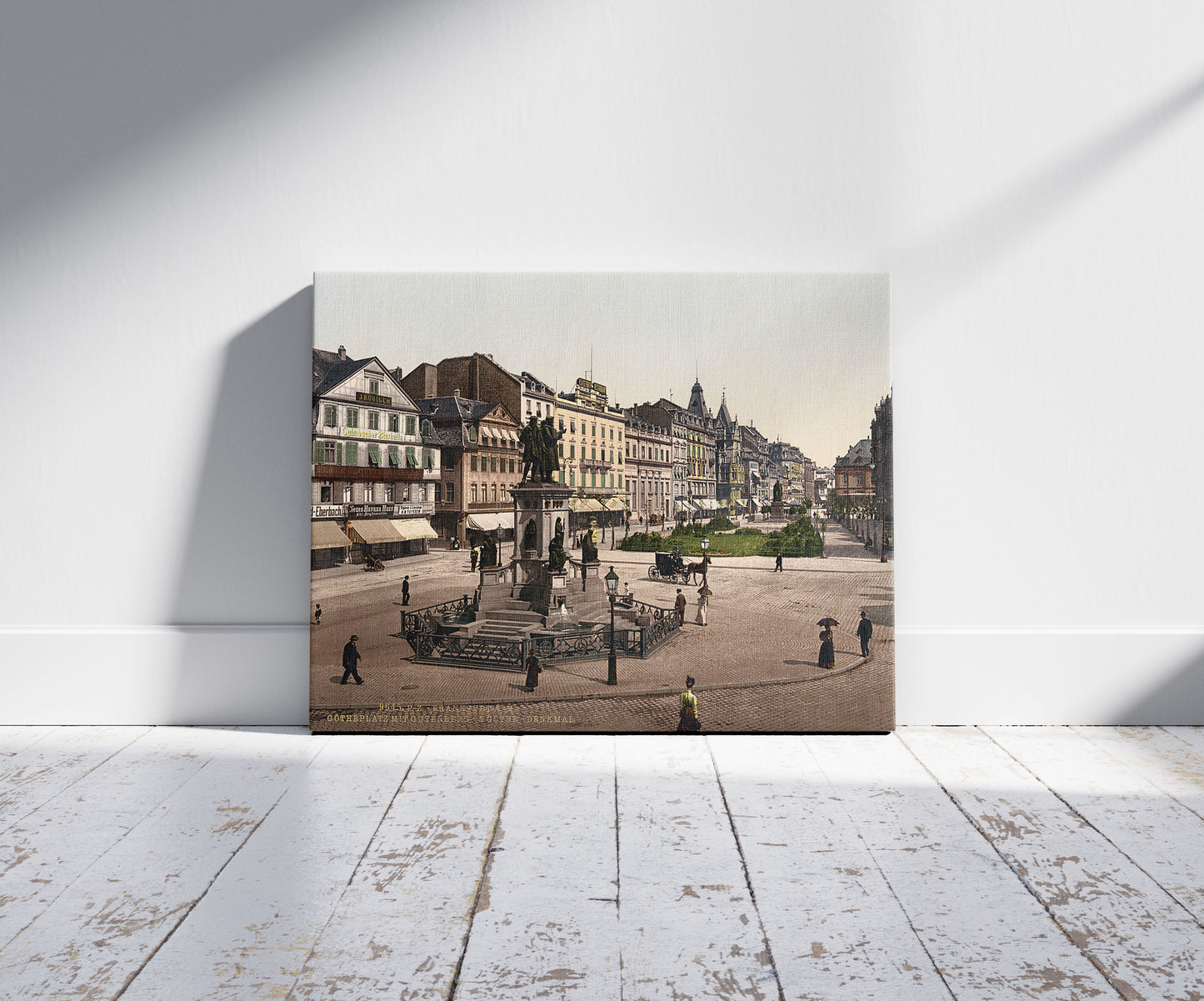 A picture of Goethe's Place and Goethe-Gutenburg Monument, Frankfort on Main (i.e. Frankfurt am Main), Germany, a mockup of the print leaning against a wall