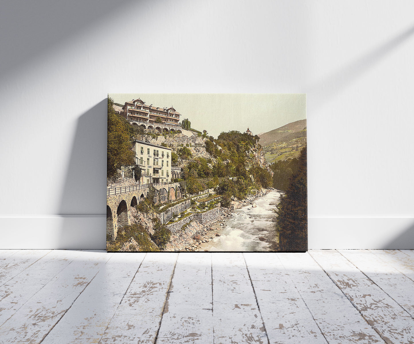 A picture of Meran, Gilf-Anlagen and Zenoberg (i.e., Zenoburg), Tyrol, Austro-Hungary, a mockup of the print leaning against a wall