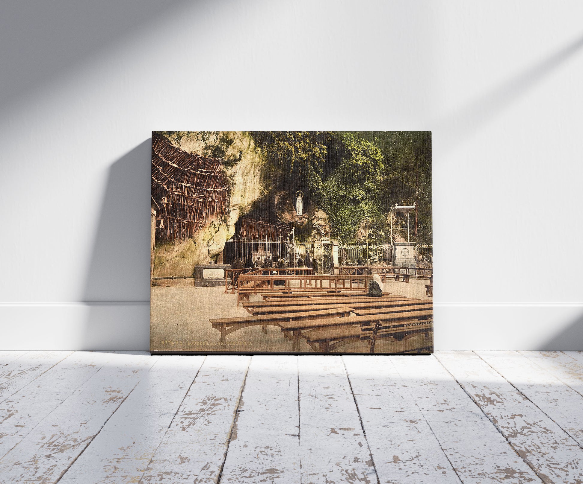 A picture of The grotto of Notre Dame, Lourdes, Pyrenees, France, a mockup of the print leaning against a wall