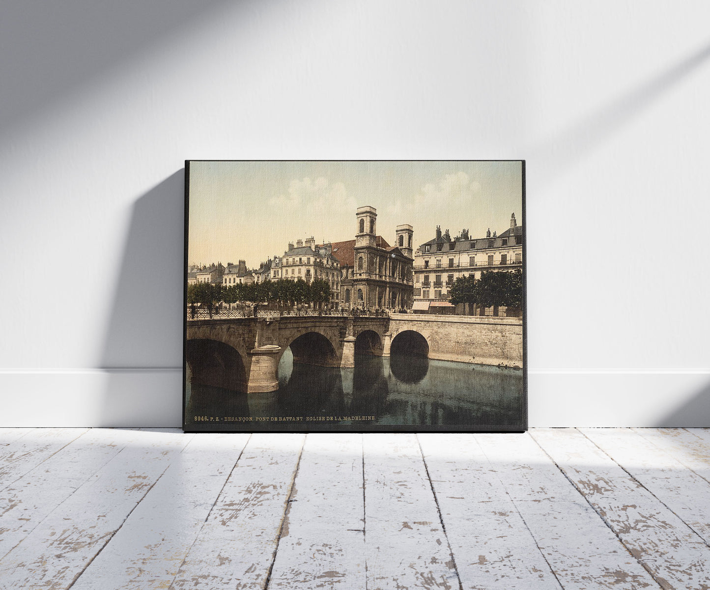 A picture of The swing bridge and Madeleine church, Besançon, France, a mockup of the print leaning against a wall