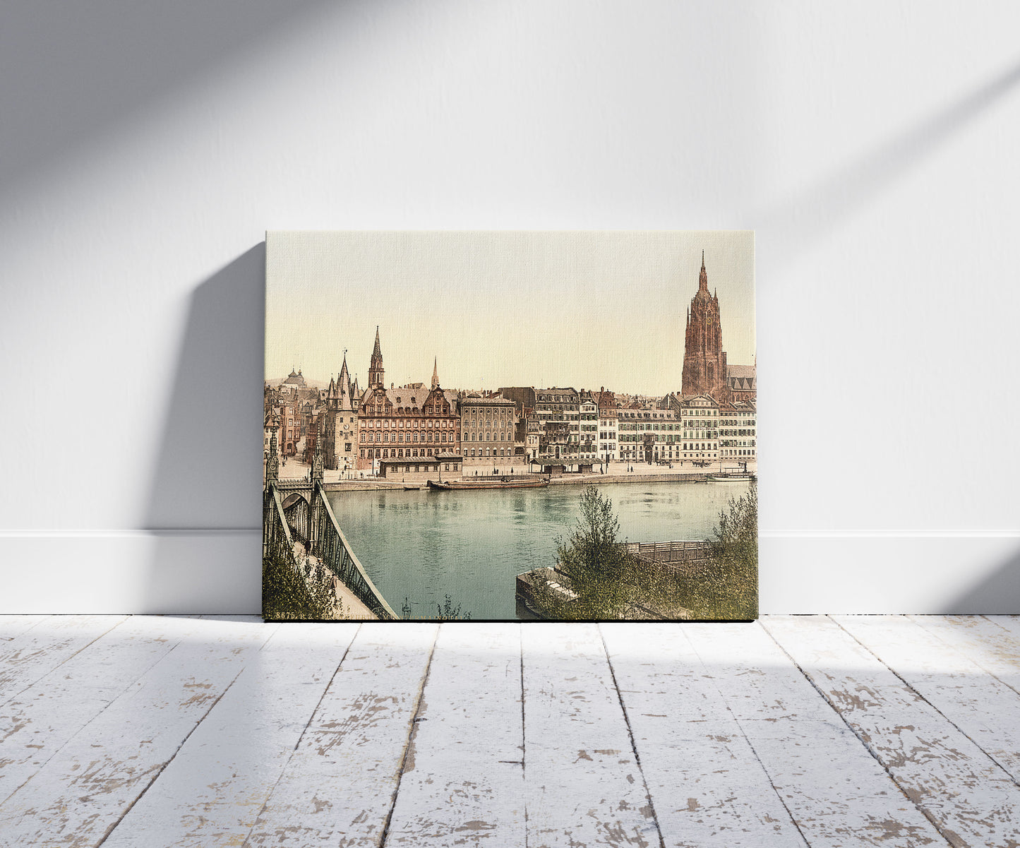 A picture of Untermainquai, Saalhof and Cathedral, Frankfort on Main (i.e. Frankfurt am Main), Germany, a mockup of the print leaning against a wall