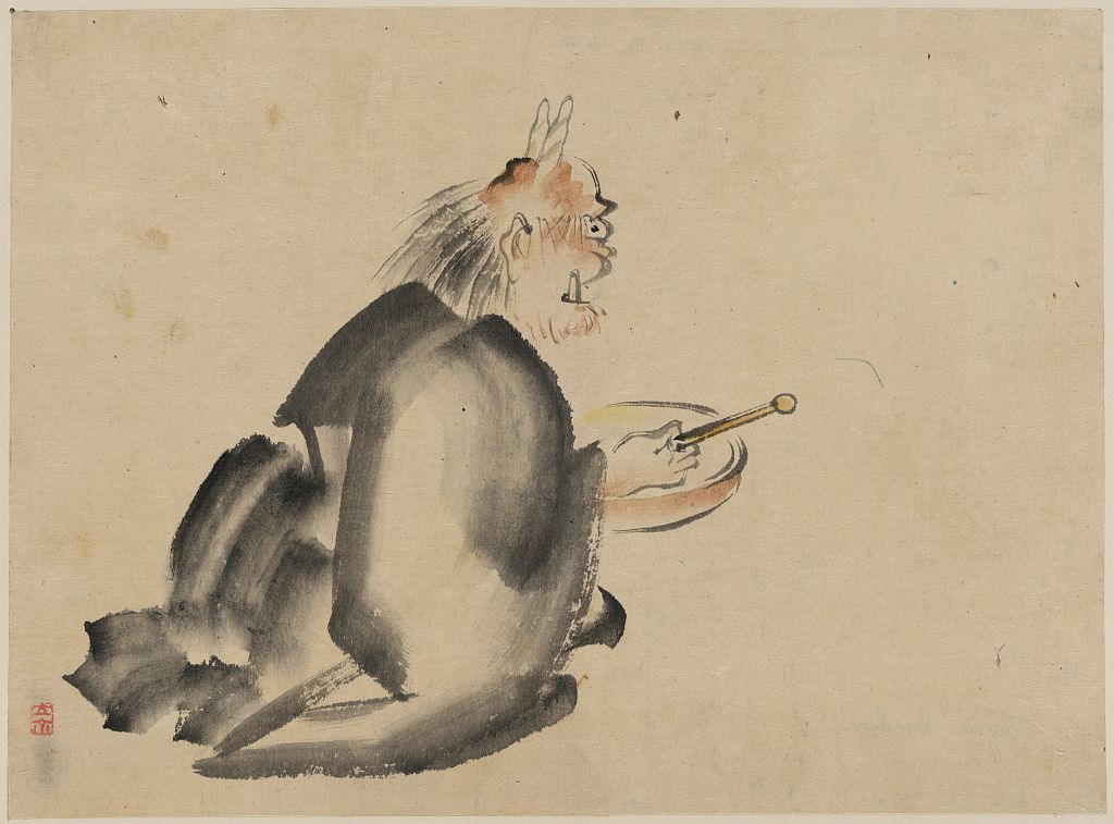 A picture of A monk wearing mask(?) with horns, sitting on the ground, beating a drum