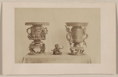 A picture of Tall, metal, ornate plant stands and figurine, all with dragon motif, on a table