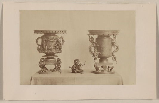 A picture of Tall, metal, ornate plant stands and figurine, all with dragon motif, on a table
